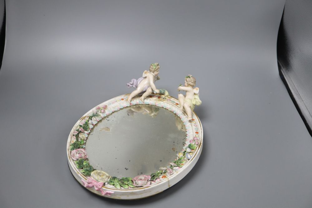 A German floral encrusted porcelain wall mirror, surmounted with winged cherubs, overall length 33cm